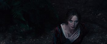 Movie still from “Into the Woods” (2014), directed by Rob Marshall – A woman in a red and black dress sitting on the ground next to a tree; Medium shot, High angle