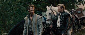 Movie still from “Into the Woods” (2014), directed by Rob Marshall – Two men standing next to a white horse in a forest; Medium shot, Over the shoulder angle