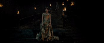 Movie still from “Into the Woods” (2014), directed by Rob Marshall – A woman in a gold dress standing on some steps; Wide shot, Low angle