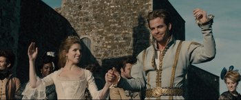 Movie still from “Into the Woods” (2014), directed by Rob Marshall – A man and a woman holding hands in front of a brick building; Medium shot, Low angle