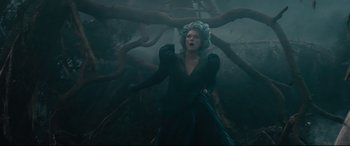 Movie still from “Into the Woods” (2014), directed by Rob Marshall – A woman in a black dress standing next to a tree; Medium shot, Low angle