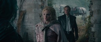 Movie still from “Into the Woods” (2014), directed by Rob Marshall – A man and a woman standing next to each other in front of a stone wall; Medium shot, Low angle