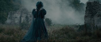 Movie still from “Into the Woods” (2014), directed by Rob Marshall – A woman in a black dress standing in a grassy field; Wide shot, Over the shoulder angle