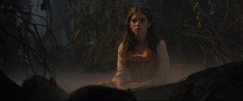 Movie still from “Into the Woods” (2014), directed by Rob Marshall – A woman sitting on the ground in front of a tree; Medium shot, Over the shoulder angle