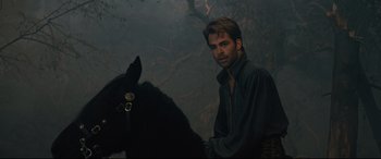 Movie still from “Into the Woods” (2014), directed by Rob Marshall – A man standing next to a horse in a forest; Medium shot, Over the shoulder angle