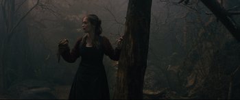 Movie still from “Into the Woods” (2014), directed by Rob Marshall – A woman standing next to a tree in the woods; Medium shot, Over the shoulder angle