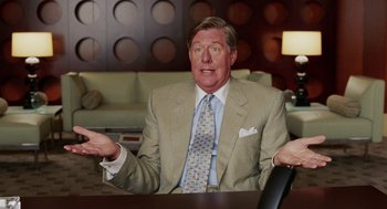 Movie still from “Intolerable Cruelty” (2003), directed by Joel Coen – A man wearing a suit and tie sitting at a table; Medium shot, High angle