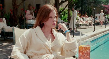 Movie still from “Intolerable Cruelty” (2003), directed by Joel Coen – A woman sitting at an outdoor table in a bathrobe; Medium shot, Over the shoulder angle