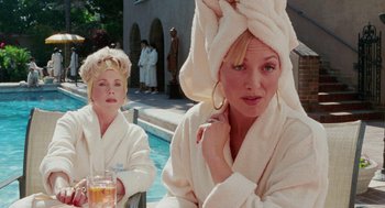 Movie still from “Intolerable Cruelty” (2003), directed by Joel Coen – A woman and a child in white robes next to a pool; Medium shot, Over the shoulder angle