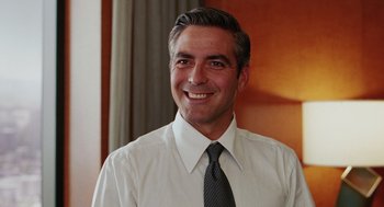 Movie still from “Intolerable Cruelty” (2003), directed by Joel Coen – A man in a white dress shirt and tie smiling; Close Up shot, Over the shoulder angle