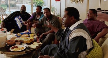 Movie still from “Intolerable Cruelty” (2003), directed by Joel Coen – A group of men sitting around a table with food; Medium shot, High angle
