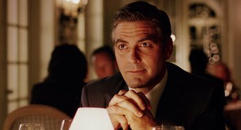 Movie still from “Intolerable Cruelty” (2003), directed by Joel Coen – A man sitting at a table with his hands clasped together; Close Up shot, Low angle