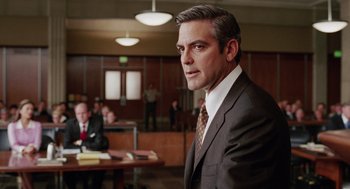 Movie still from “Intolerable Cruelty” (2003), directed by Joel Coen – A man in a suit and tie in a courtroom; Close Up shot, Over the shoulder angle