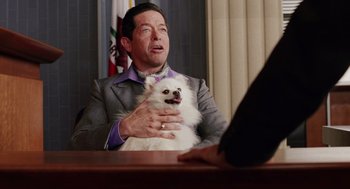 Movie still from “Intolerable Cruelty” (2003), directed by Joel Coen – A man sitting at a table with a dog; Close Up shot, Over the shoulder angle