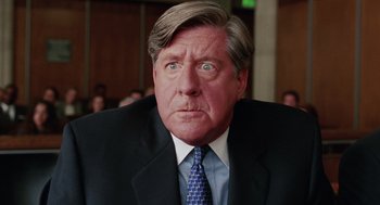 Movie still from “Intolerable Cruelty” (2003), directed by Joel Coen – An older man in a suit and tie with his eyes wide open; Close Up shot, Low angle