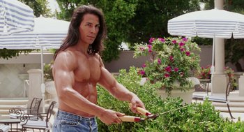 Movie still from “Intolerable Cruelty” (2003), directed by Joel Coen – A man with long black hair holding a pair of scissors; Medium shot, Over the shoulder angle