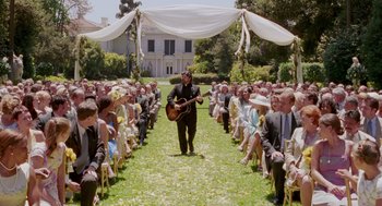 Movie still from “Intolerable Cruelty” (2003), directed by Joel Coen – A man playing a guitar in front of an audience; Wide shot, Over the shoulder angle