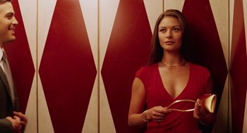 Movie still from “Intolerable Cruelty” (2003), directed by Joel Coen – A woman in a red dress holding a whip in front of a red wall; Medium shot, Low angle