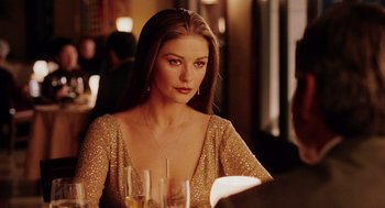 Movie still from “Intolerable Cruelty” (2003), directed by Joel Coen – A woman sitting at a table with a glass of wine; Close Up shot, Over the shoulder angle