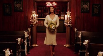 Movie still from “Intolerable Cruelty” (2003), directed by Joel Coen – A woman in a white dress holding a bouquet of flowers; Wide shot, Low angle