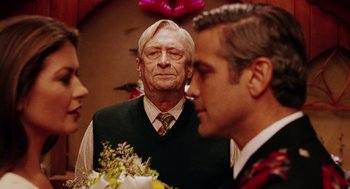 Movie still from “Intolerable Cruelty” (2003), directed by Joel Coen – A man and a woman standing next to each other holding flowers; Close Up shot, Over the shoulder angle