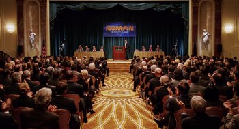 Movie still from “Intolerable Cruelty” (2003), directed by Joel Coen – A crowd of people sitting in front of a podium; Extreme Wide shot, High angle