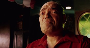 Movie still from “Intolerable Cruelty” (2003), directed by Joel Coen – An older bald man wearing a red shirt; Close Up shot, Low angle