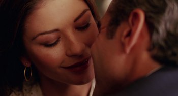 Movie still from “Intolerable Cruelty” (2003), directed by Joel Coen – A person kissing another person on the cheek; Close Up shot, Over the shoulder angle