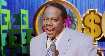 Movie still from “Intolerable Cruelty” (2003), directed by Joel Coen – A man in a suit and a tie holding a microphone in his hand; Close Up shot, Low angle