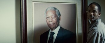 Movie still from “Invictus” (2009), directed by Clint Eastwood – An older man wearing a suit and tie in front of a wall; Close Up shot, Low angle