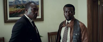 Movie still from “Invictus” (2009), directed by Clint Eastwood – Two men standing next to each other in front of a wall; Close Up shot, Low angle