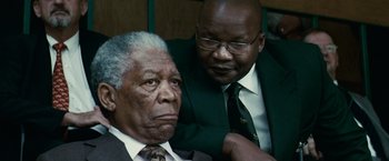 Movie still from “Invictus” (2009), directed by Clint Eastwood – A man in a suit and tie and another man in a suit; Close Up shot, Over the shoulder angle