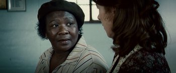 Movie still from “Invictus” (2009), directed by Clint Eastwood – A woman wearing a hat talking to another woman; Close Up shot, Over the shoulder angle