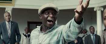 Movie still from “Invictus” (2009), directed by Clint Eastwood – A man with a hat is holding his hand up; Close Up shot, Low angle