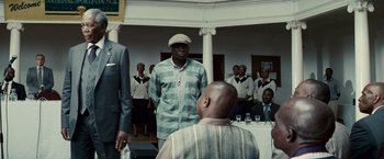 Movie still from “Invictus” (2009), directed by Clint Eastwood – A group of men standing around a table with drinks on it; Medium shot, Low angle