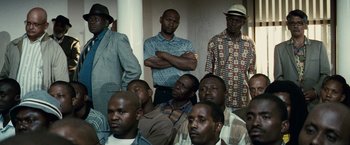 Movie still from “Invictus” (2009), directed by Clint Eastwood – A group of men standing next to each other in front of a wall; Medium shot, Over the shoulder angle