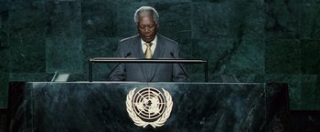 Movie still from “Invictus” (2009), directed by Clint Eastwood – A man standing at a podium in front of a united nations sign; Medium shot, Low angle