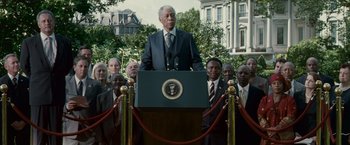 Movie still from “Invictus” (2009), directed by Clint Eastwood – A group of men standing around a podium with a man standing at the top of the podium; Wide shot, Low angle