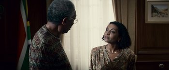 Movie still from “Invictus” (2009), directed by Clint Eastwood – A man and a woman standing next to each other in front of a window; Close Up shot, Over the shoulder angle