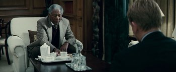 Movie still from “Invictus” (2009), directed by Clint Eastwood – An older man sitting at a table in a room; Medium shot, Over the shoulder angle