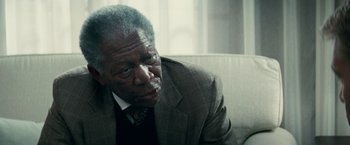 Movie still from “Invictus” (2009), directed by Clint Eastwood – An older man wearing a suit and tie; Close Up shot, Over the shoulder angle