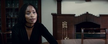 Movie still from “Invictus” (2009), directed by Clint Eastwood – A woman sitting at a table in front of a fire place; Close Up shot, Over the shoulder angle