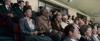 Movie still from “Invictus” (2009), directed by Clint Eastwood – A group of people sitting in a row on a train; Medium shot, High angle