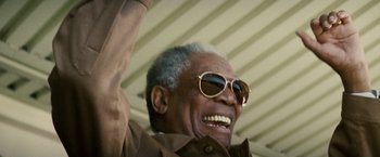Movie still from “Invictus” (2009), directed by Clint Eastwood – An older man wearing sunglasses raising his hand; Close Up shot, Low angle