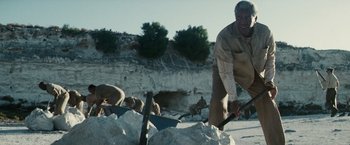 Movie still from “Invictus” (2009), directed by Clint Eastwood – An old man digging a hole in the ground; Medium shot, Low angle