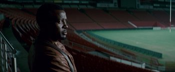 Movie still from “Invictus” (2009), directed by Clint Eastwood – A man standing in an empty stadium looking off into the distance; Medium shot, Low angle