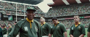 Movie still from “Invictus” (2009), directed by Clint Eastwood – A group of men standing on top of a football field; Close Up shot, Low angle