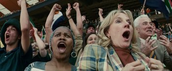 Movie still from “Invictus” (2009), directed by Clint Eastwood – A group of people in the stands with their hands up; Close Up shot, Low angle