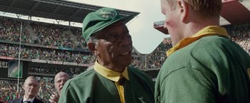 Movie still from “Invictus” (2009), directed by Clint Eastwood – An older man wearing a green and yellow hat; Close Up shot, Over the shoulder angle
