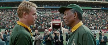 Movie still from “Invictus” (2009), directed by Clint Eastwood – Two men talking to each other in front of a crowd; Medium shot, Low angle